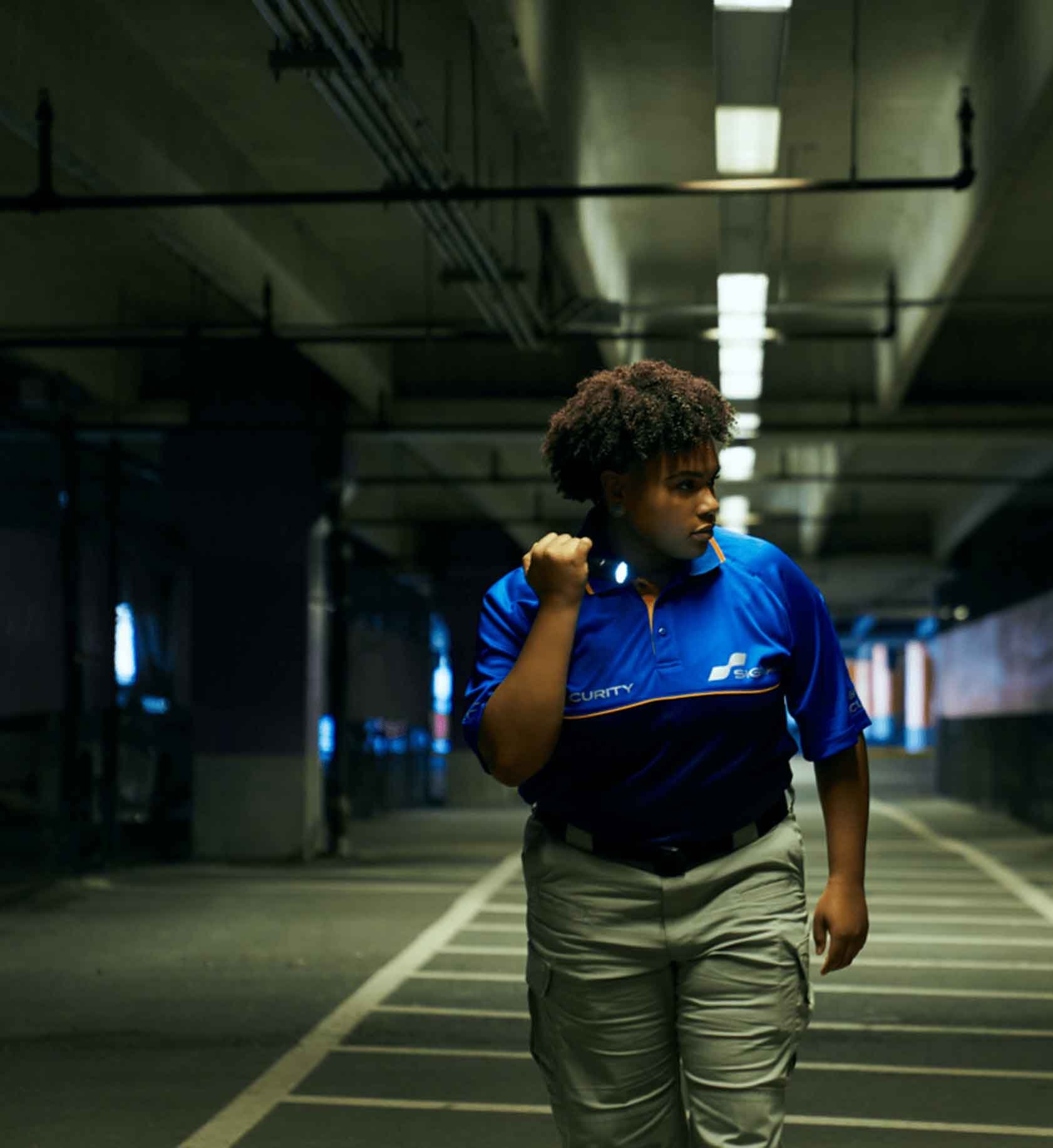 Signal employee shining flashlight while walking through a parking garage