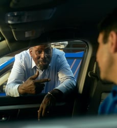 person leaning on passenger side window of a car to talk