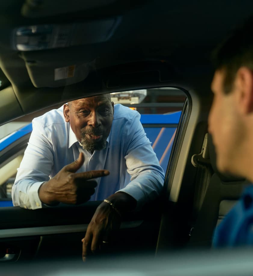 person leaning through the passenger side window of a car to talk to a Signal employee